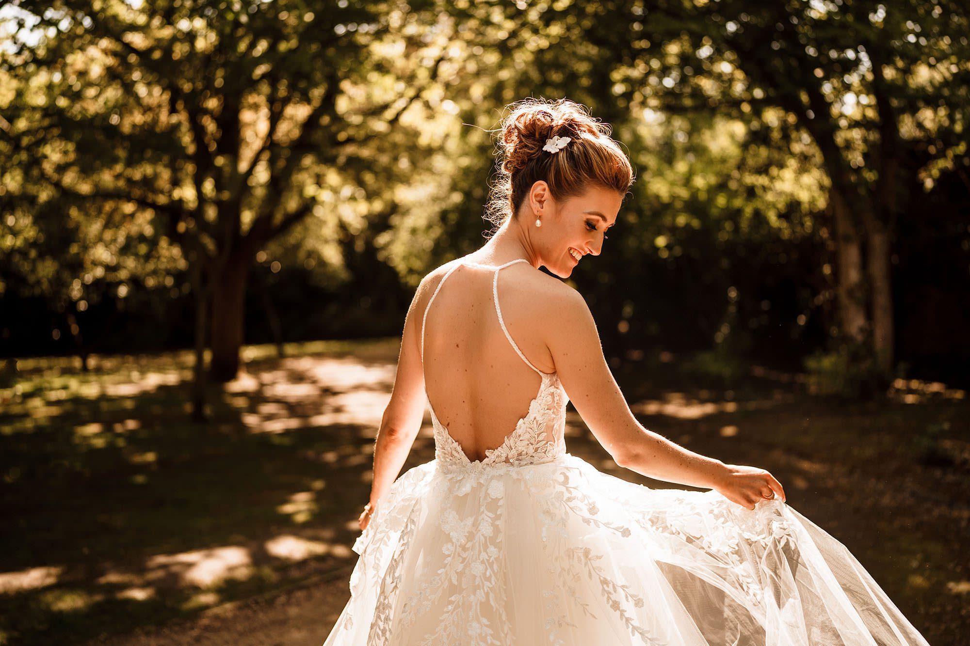 bride looks at her wedding dress in the Lake District sunlight