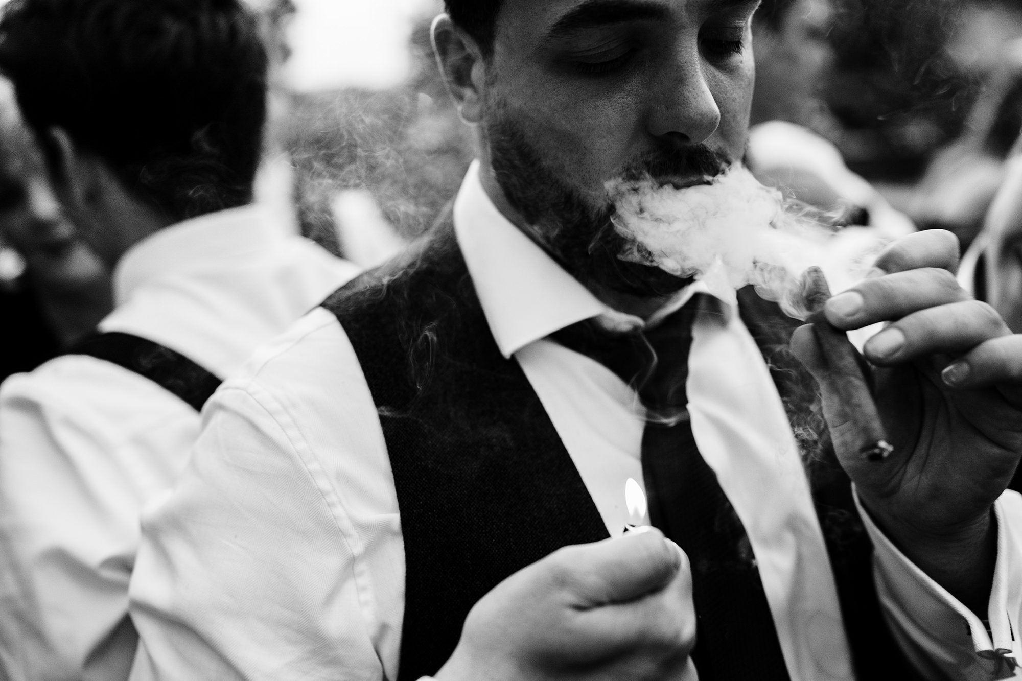 groom lights up a cigar after his lakes wedding