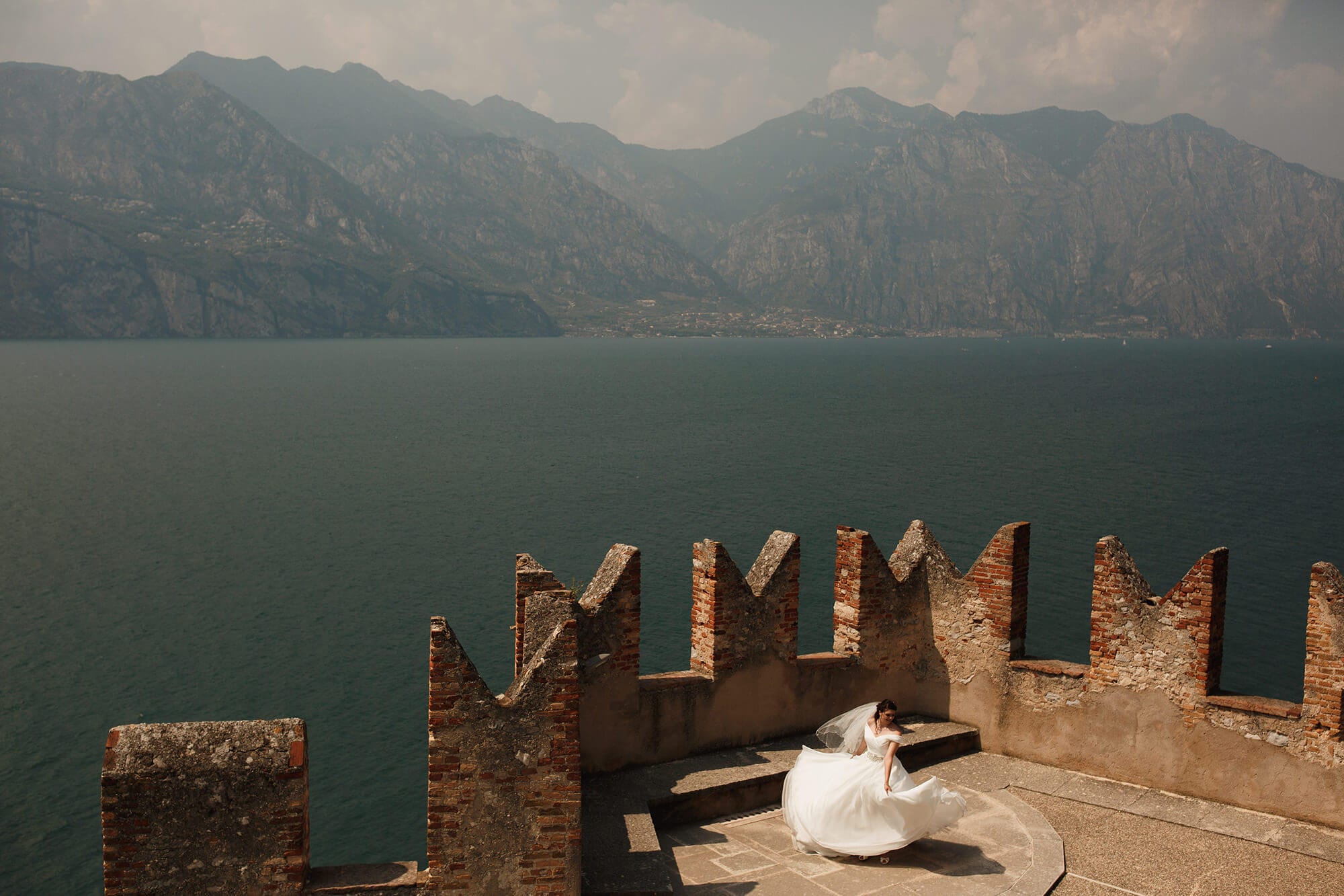 Bride twirls in beautiful dress at lake Garda castle.