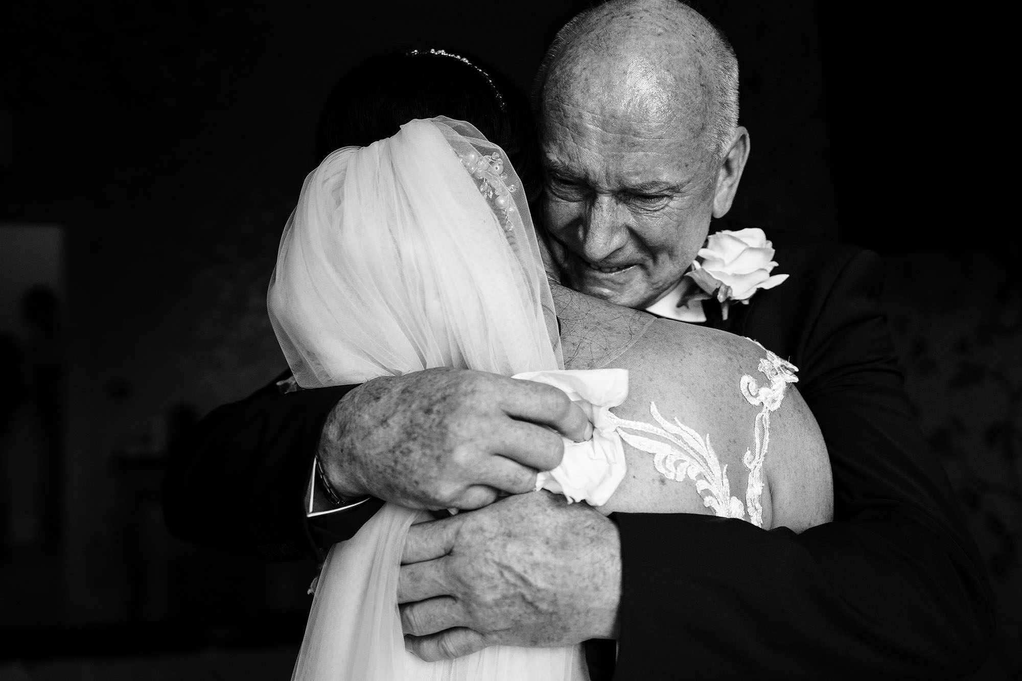 Emotional father proudly embraces his bride daughter after Italian wedding ceremony.